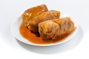 Close up view of cabbage rolls stuffed with ground beef, rice and baked with tomato sauce on plate over white background with free text space. Top view, flat lay