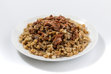 Barley porridge in a bowl with meat on the white background