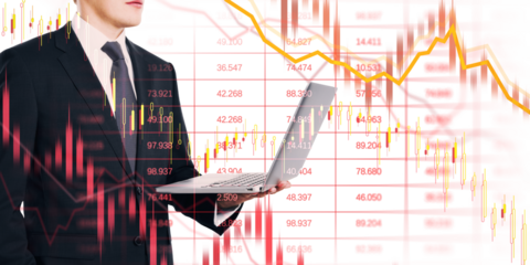 Businessman in suit with laptop overlaid by crashing stock charts, red arrows, and downward lines on white background, showing financial collapse