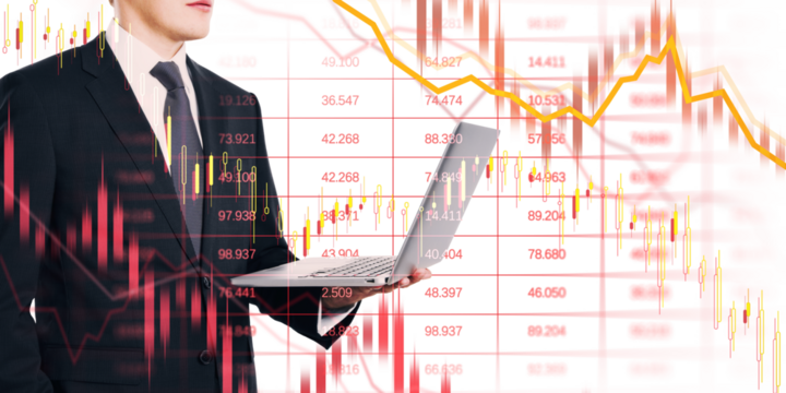 Businessman in suit with laptop overlaid by crashing stock charts, red arrows, and downward lines on white background, showing financial collapse