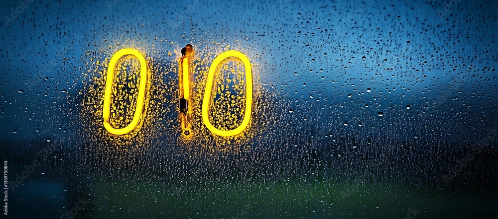 Poster illuminated numbers are reflected through wet window panes