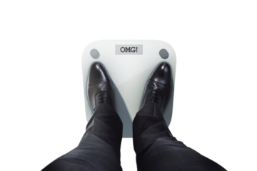 Closeup of a person in black formal shoes standing on a digital scale displaying OMG! on a clean white background, concept of weight shock