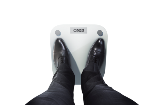 Closeup of a person in black formal shoes standing on a digital scale displaying OMG! on a clean white background, concept of weight shock