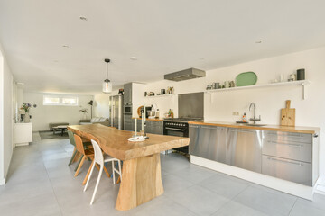 A spacious and contemporary kitchen featuring a wooden dining table, stainless steel appliances, and a sleek design, perfect for modern living.