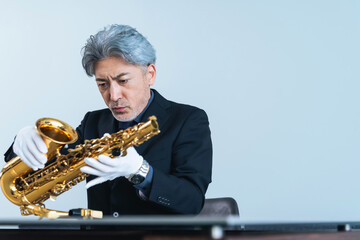 サックスを確認するミドルエイジ男性　鑑定士・リペアマン・楽器職人