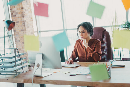 Focused businesswoman analyzing documents in a bright office workspace with colorful reminders and a professional setup