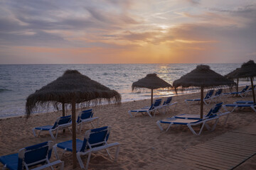 Sunset on the beach with sunbeds and umbrellas