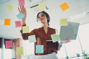 Young professional woman planning in a creative office with sticky notes aligned on glass