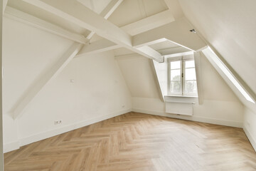 A modern attic interior with sloped ceilings, large windows, and wooden flooring creating a warm and inviting atmosphere. Ideal for creative spaces or cozy living.