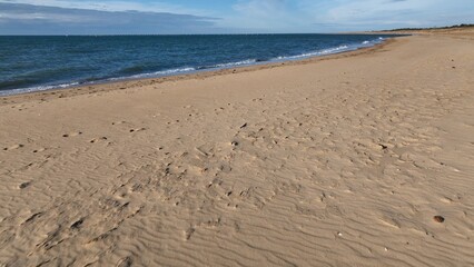 Virginia Beach, VA coastline sandy beaches with gentle ocean surf with sunlight on water in late afternoon on peaceful warm day outdoors in nature