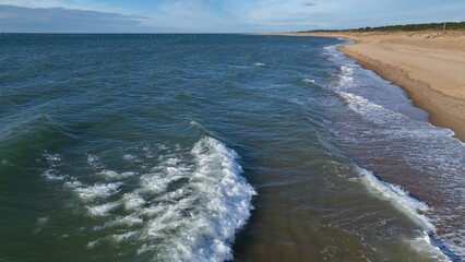 Virginia Beach, VA coastline sandy beaches with gentle ocean surf with sunlight on water in late afternoon on peaceful warm day outdoors in nature