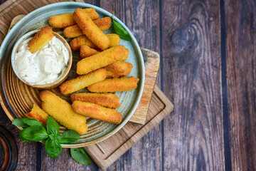  Mozzarella sticks .Italian cheese breaded  oven baked with  fresh basil on wooden background.Italian street food.
