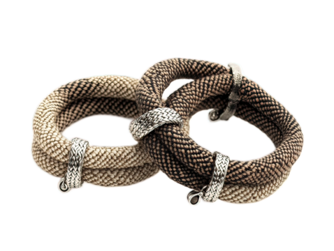 Woven textile bracelet with sliding knot closure and small silver charm, arranged in S-curve on white background
