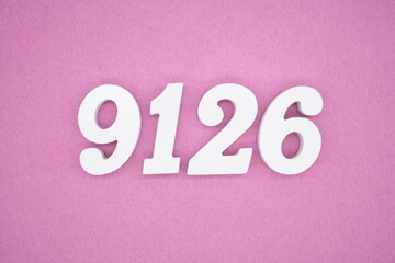 The numbers are made of white painted wood and placed on a pink paper background.
