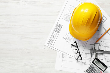 Different engineering drawings, hard hat, pencil, vernier caliper, calculator and glasses on light...