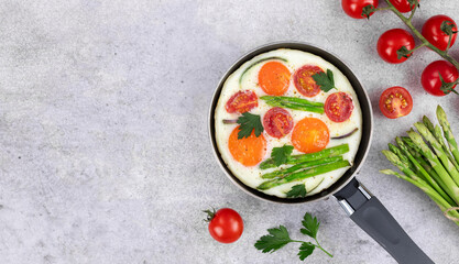 Fried eggs with vegetables in a frying pan on a gray background. Top view. Copy space. Breakfast food.