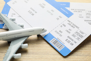 Travel agency. Flight tickets and plane model on wooden table, closeup