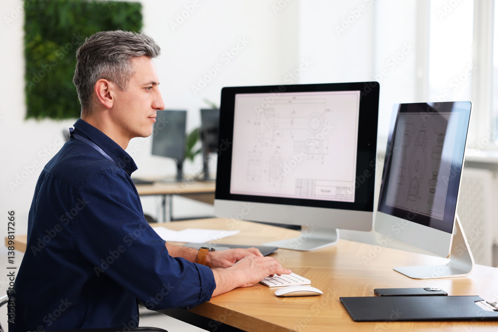Poster engineer working with digital drawings at table in office