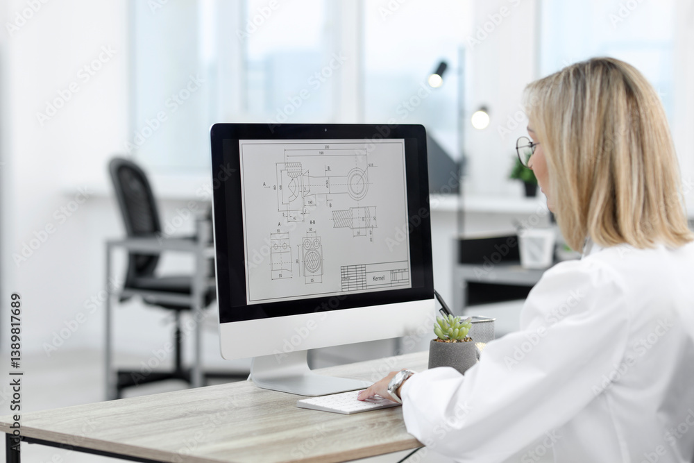 Poster technician making digital engineering drawing on computer at desk in office