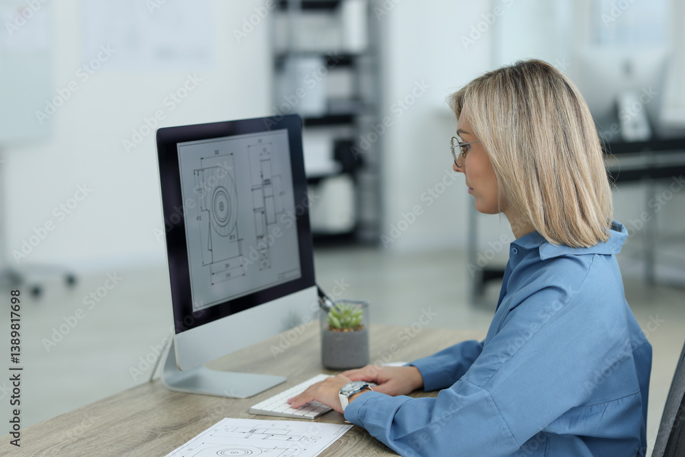 Poster technician making digital engineering drawing on computer at desk in office