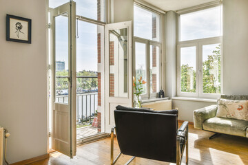A spacious living room featuring large windows that invite natural light, an open balcony view, and modern furnishings for comfort and style.