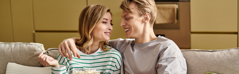 Young couple enjoying cozy moments together at home with popcorn and laughter