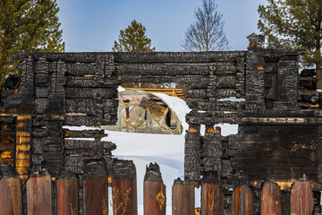 Close-up of black frame of a wooden country house after fire. Blackboards burned during a fire in...