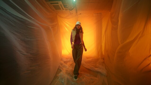 Fototapeta Woman Walking Through Ethereal Space with Orange Lighting and Draped Fabric