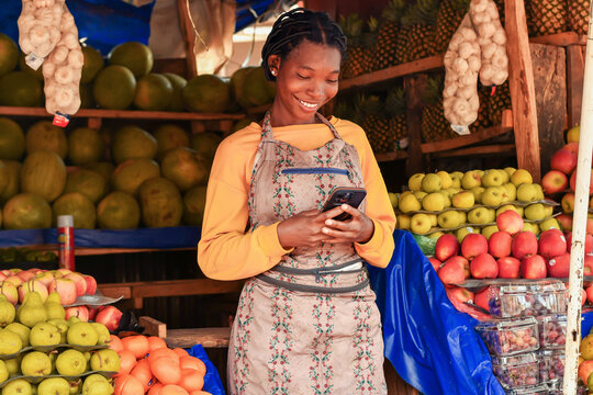 medium shot of salesperson using mobile phone at fruit market stand