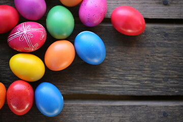 The Easter colorful eggs are lying on the wooden table. One egg is traditionally decorated.