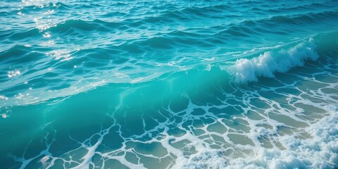 Fototapeta premium A powerful wave crashes onto the sandy shore, sending white foam spraying into the air. The vibrant blue ocean glistens under the sunlight, creating a serene yet dynamic scene.