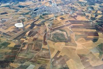 Beautiful aerial view of brown and yellow fields. Unkonwn city at the background.
