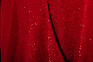 Red glittery fabric with soft folds, ideal for festive and fashion backgrounds.