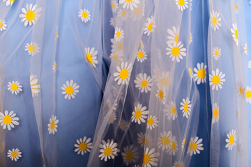 Delicate daisy-patterned sheer fabric, ideal for spring fashion or floral themes.