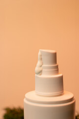 Close-up of a white cosmetic pump bottle with a droplet of cream, set against a minimal warm beige background. Ideal for skincare product presentations, beauty ads, and self-care concepts.