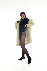 Stylish young woman in a chic fur coat and bold fashion choices striking a confident pose