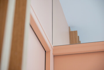 Gros plan sur une porte aux teintes saumon encadrée de miroirs