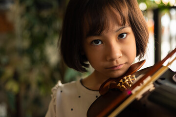 Asian girl passionately plays the violin, demonstrating focus and dedication during a music lesson. Her precise movements and deep concentration highlight her growing talent as a young musician.