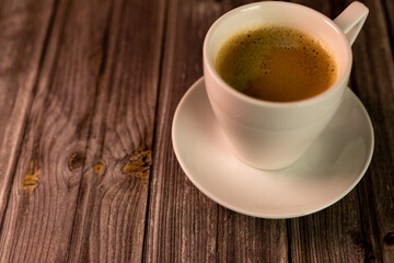 Coffee in a white cup on a wooden background. Hot aromatic coffee