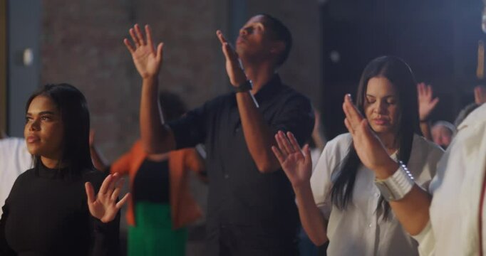 Diverse congregation raising hands in worship, celebrating spirituality and faith in a church service, with a glowing cross as a central focus