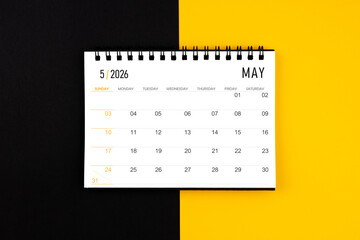 May 2026 desk calendar on black and yellow background, Flat lay.