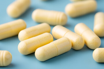 Close-Up Shot of Multiple Pale Yellow Capsules on a Light Blue Surface Pharmaceutical Medicine Health Supplements