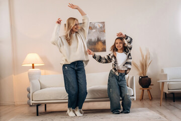 Standing and dancing, fun. Mother and daughter are together in domestic room