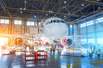 Passenger aircraft jet on maintenance of engine and fuselage repair in airport hangar red and blue...