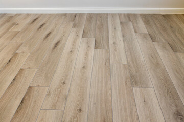 Laminated wood floor with white wall. Empty room with floating laminate in new apartmen