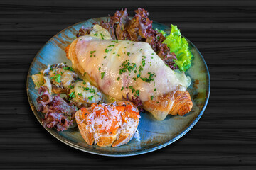 croisant topped with ham and cheese, toasted white bread with tomato and parmesan cheese