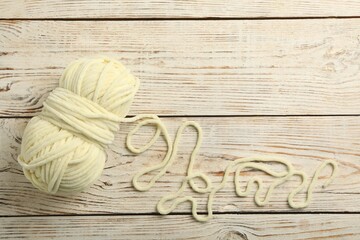 Soft woolen yarn on white wooden background, top view. Space for text