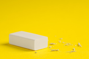 One eraser and scraps on yellow background, closeup. Space for text