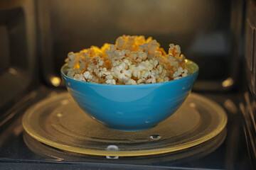Bowl of tasty popcorn in microwave oven, closeup
