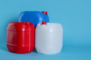 Different plastic canisters on light blue background, space for text